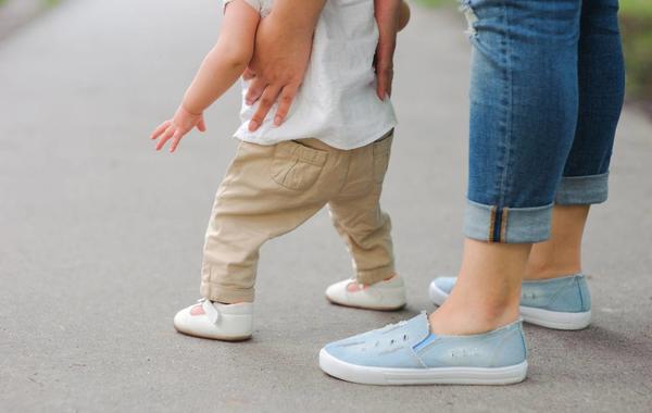 صورة لأم تساعد طفلتها على المشي